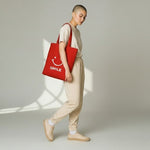 WharfPrint red cotton canvas tote bag with a white smile graphic worn by a model in a beige loungewear set
